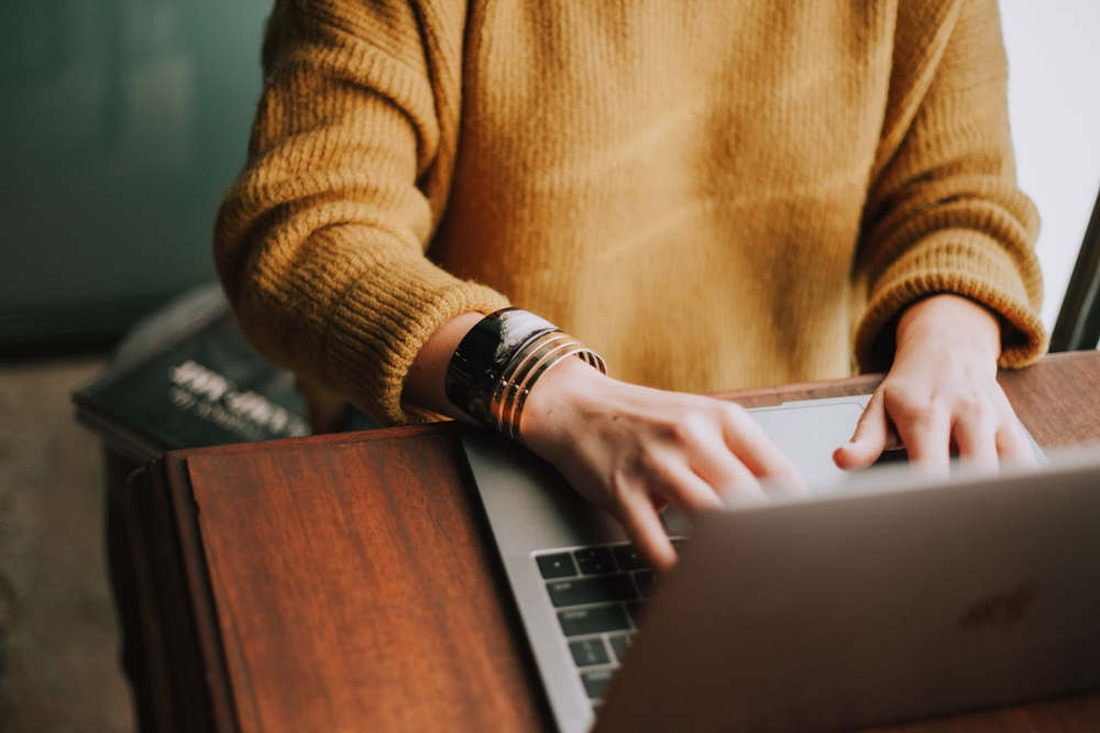 Person in sweater sitting at a laptop